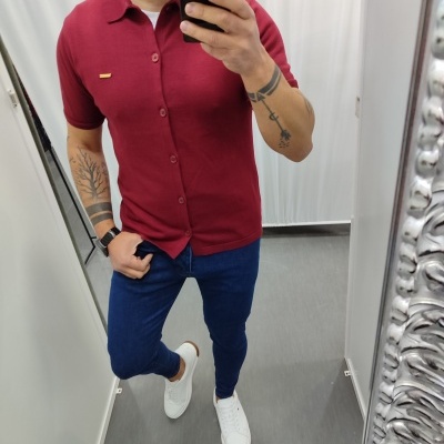 Homem a vestir camisola polo vermelha, calças azul escuro e sapatilhas brancas em provador