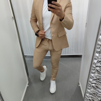 Homem a tirar selfie com fato bege, t-shirt branca e ténis brancos