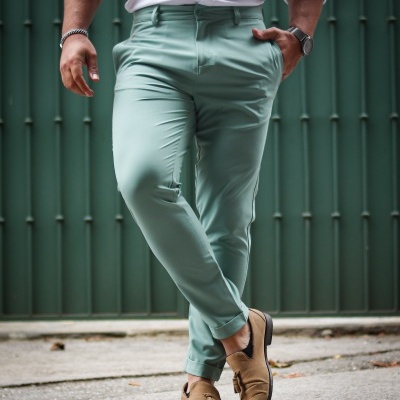 homem com calças azul claro, camisa branca e sapatos castanhos em fundo urbano