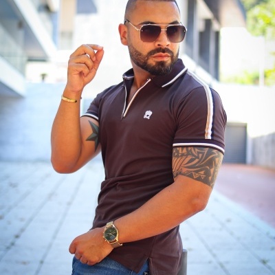 Homem com polo preta e óculos de sol num ambiente urbano