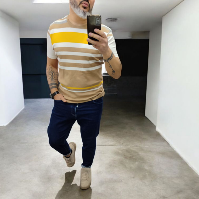 Homem com t-shirt de riscas coloridas tirando selfie em espelho