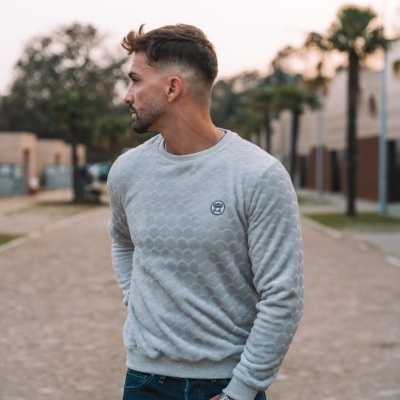 Homem com camisola cinzenta e calças de ganga em ambiente urbano