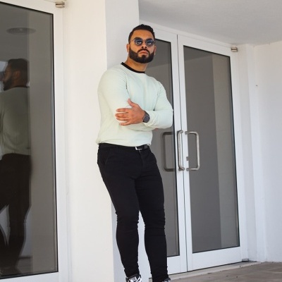 Homem de pé junto a porta dupla de vidro com roupa casual