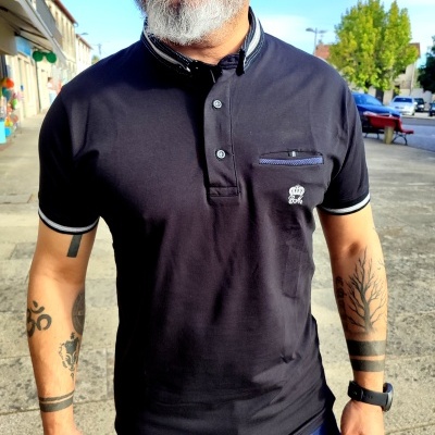 Homem vestindo polo preto com bolso e logotipo SBK em ambiente urbano