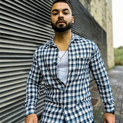 Homem com camisa xadrez azul e branca e t-shirt branca em ambiente urbano