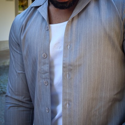 Camisa cinzenta de riscas finas com t-shirt branca por baixo, detalhes de botões e textura lisa.