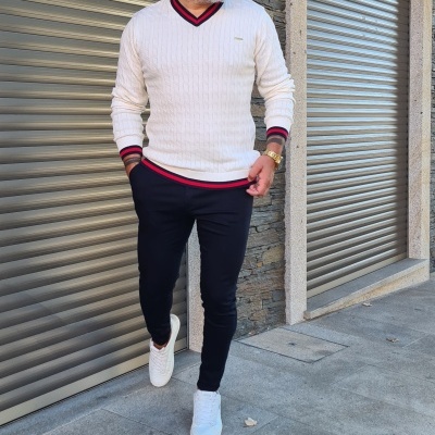 Homem com camisola branca de malha, calças pretas e sapatilhas brancas em passeio