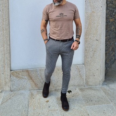 Homem com roupa casual contra parede branca de pedra.