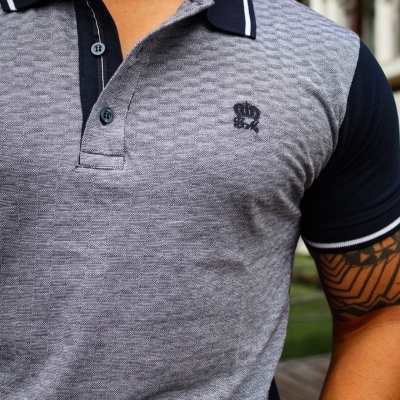 Polo cinza texturizado com mangas e gola azul escuro, logotipo bordado azul no peito, risca branca nas bordas da gola e mangas