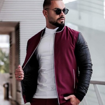 Homem com casaco bomber bordô com mangas pretas acolchoadas e óculos escuros