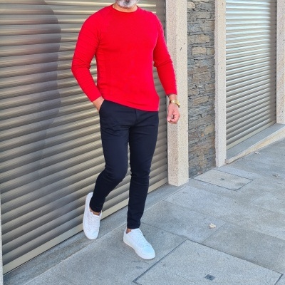 Homem com camisola vermelha, calças pretas e sapatilhas brancas em rua com portas metálicas