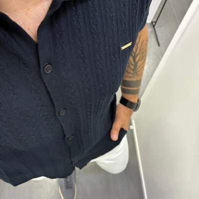 Camisa azul escura com padrão trançado e colarinho com detalhe vermelho e branco