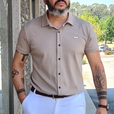 Homem com camisa bege e calças brancas em ambiente exterior