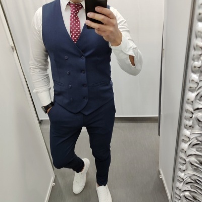 Homem vestido formal com colete azul, camisa branca e gravata vermelha com pontos brancos