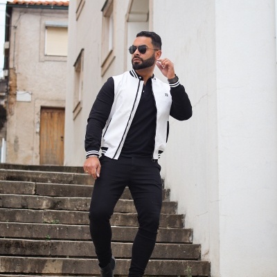 Homem com roupa preta e casaco branco perto de escadaria exterior