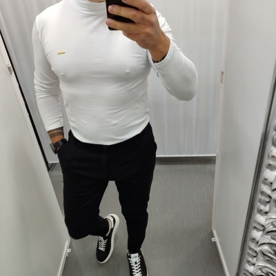 Homem com camisola branca, calças pretas e sapatilhas pretas num espelho