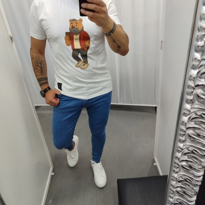 Homem a usar camiseta branca com estampa de urso e calças jeans azuis num provador