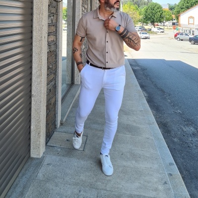 Homem com camisa bege e calças brancas em rua urbana