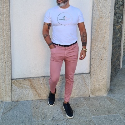 Homem com t-shirt branca e calças cor de rosa posando ao ar livre