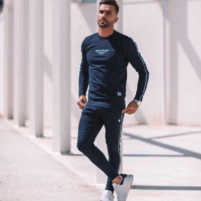 Homem com conjunto desportivo azul escuro com riscas brancas e texto na camisola