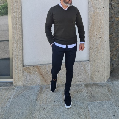 Homem com estilo casual wearing camisola preta, camisa azul, calças escuras e ténis pretos em pavimento de pedra