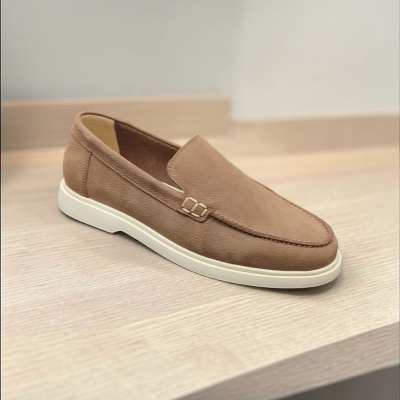 Sapato mocassim castanho claro com sola branca sobre superfície de madeira