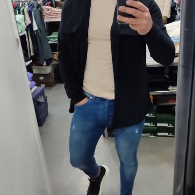 Homem com roupa casual numa loja de roupa à sua volta.
