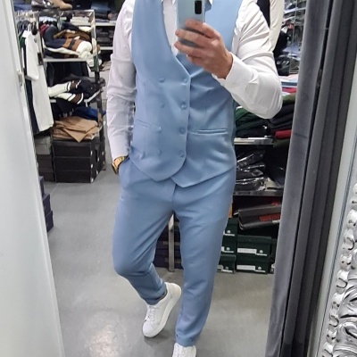 Homem vestido com fato azul claro e camisa branca numa loja de roupa