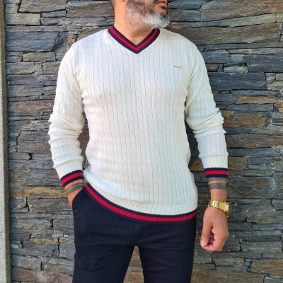 Suéter branco com riscas vermelha e azul escuro na gola e punhos, usado com calças pretas