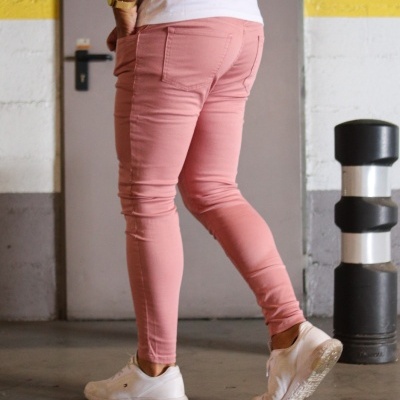 Calças de ganga rosa justas usadas por uma pessoa em ambiente interior.