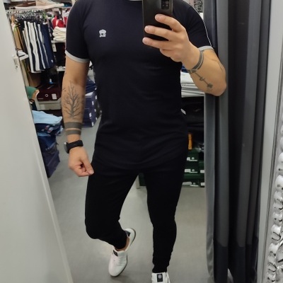 Homem vestindo conjunto preto e calçado branco numa loja de roupas