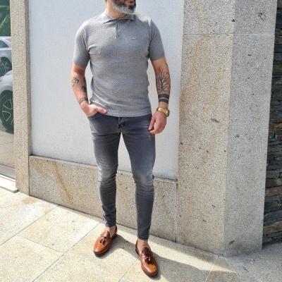 Homem com polo cinzenta, calças cinzentas e sapatos castanhos na rua