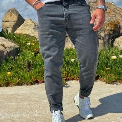 Calças cinza escuras em tecido denim com sapatilhas brancas e t-shirt branca em ambiente exterior