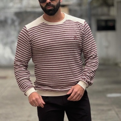 Homem com camisola às riscas creme e bordô, calças pretas e óculos escuros