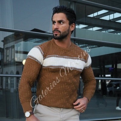 Homem com sweatshirt castanha e branca em padrão geométrico em relevo em ambiente urbano