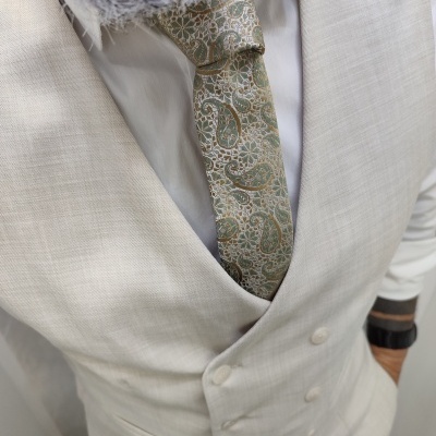 Homem com fato bege claro, gravata verde bege com padrão paisley e cachecol floral