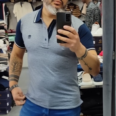 Homem com polo cinza e azul em loja de roupas