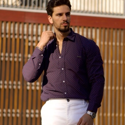 Homem com camisa azul escura estampada e calças brancas ao ar livre