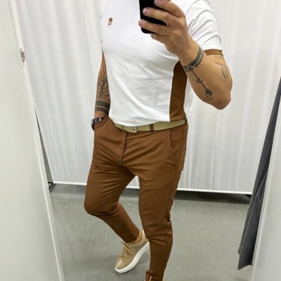 Homem em roupa casual com t-shirt branca e castanha, calças castanhas e sapatilhas bege