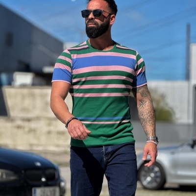 Homem a usar t-shirt de riscas coloridas com calças de ganga e óculos de sol ao ar livre