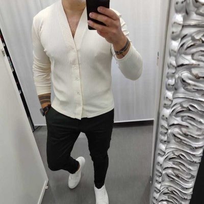 homem com camisola bege e calças pretas a tirar selfie em espelho com moldura prateada