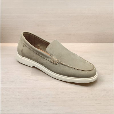 Sapato tipo mocassim bege em pele com sola branca sobre madeira clara