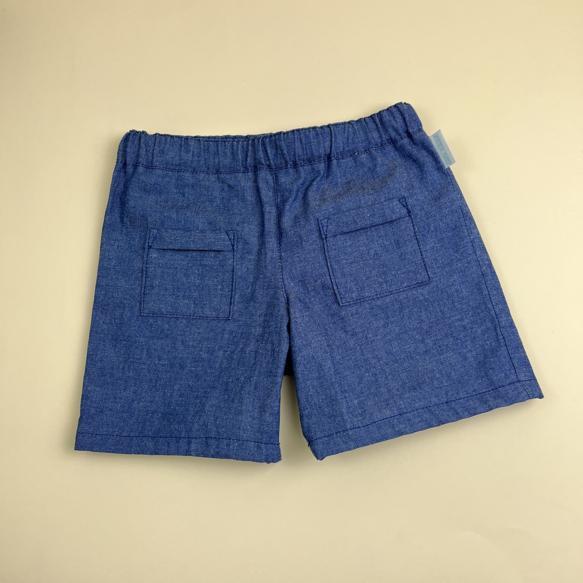 Calções azuis de criança com bolsos traseiros e cós elástico