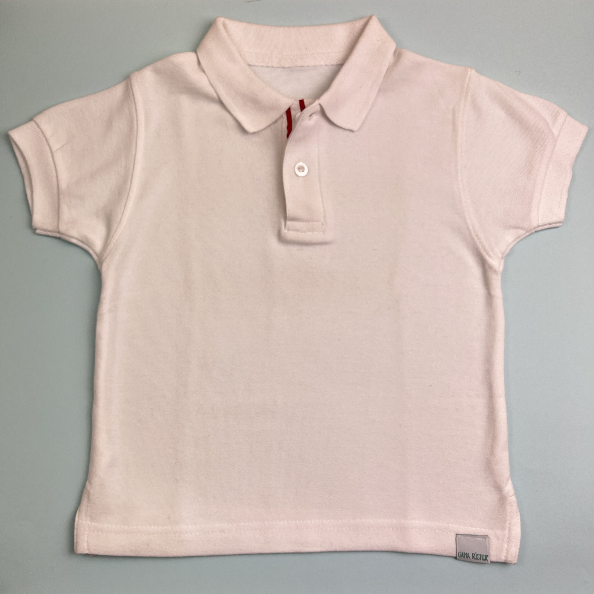 Polo rosa claro para criança em algodão com gola, botão e etiqueta pequena na bainha