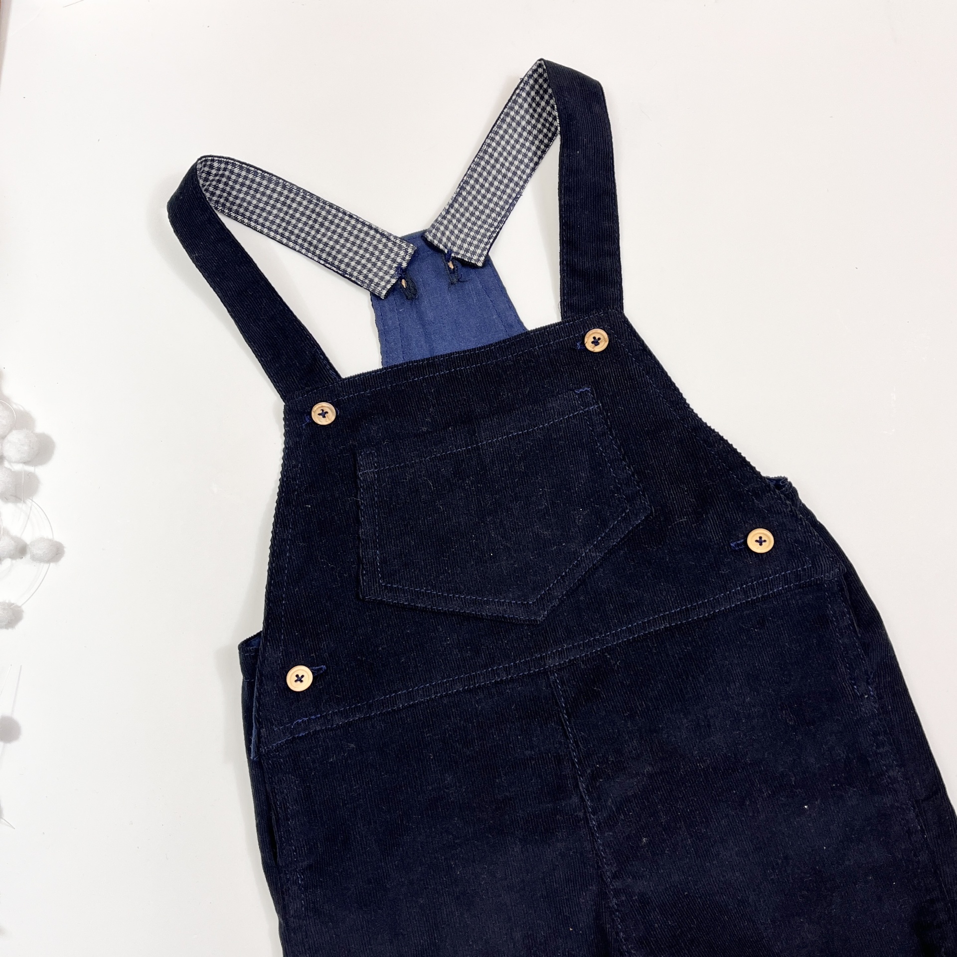 Jardineira infantil azul escura com botões e alças com padrão xadrez