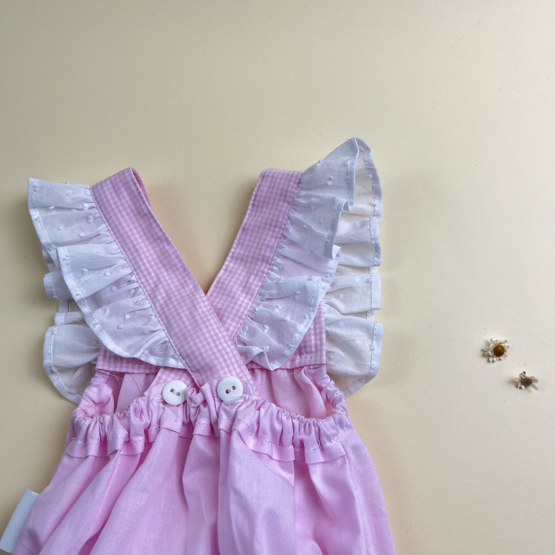 Vestido rosa de criança com alças folhadas e botões brancos