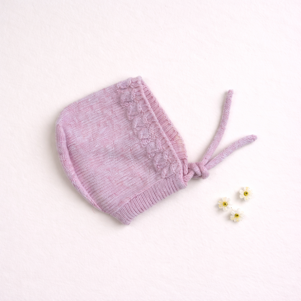 Gorro cor-de-rosa de malha com fitas e flores pequenas em fundo branco