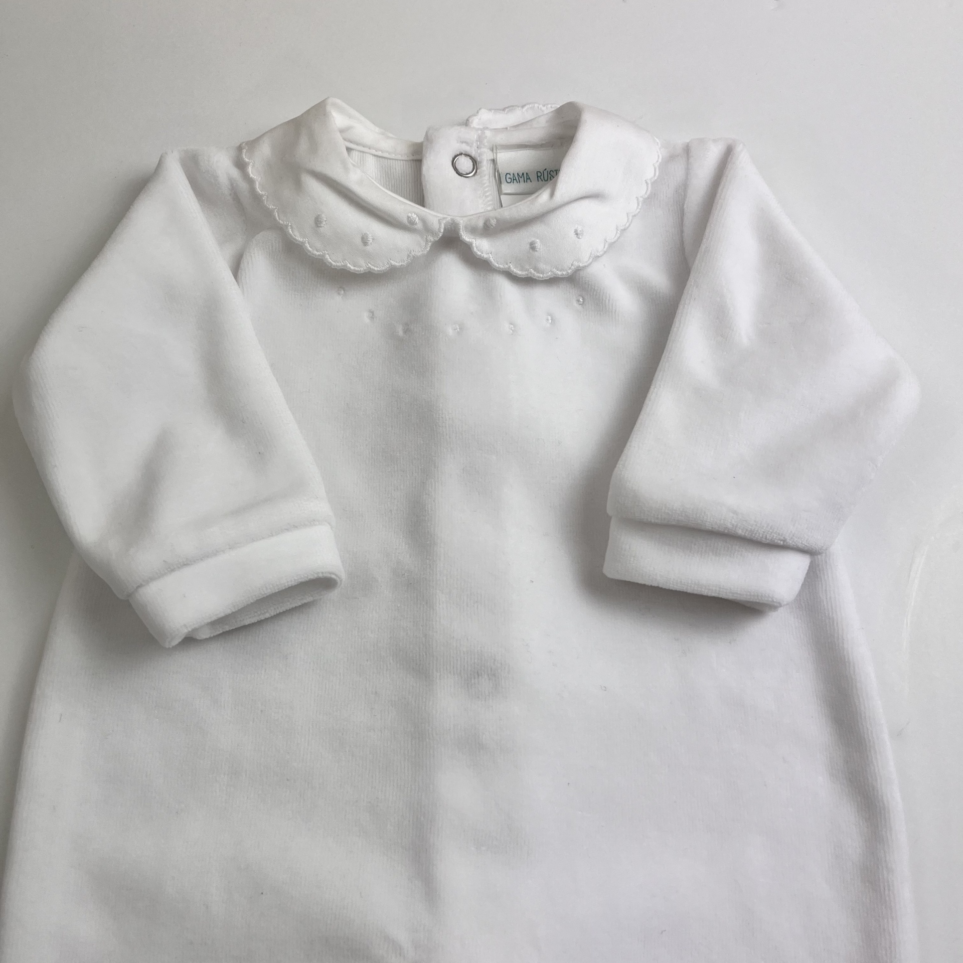 Vestuário infantil branco de manga comprida com gola redonda e botões