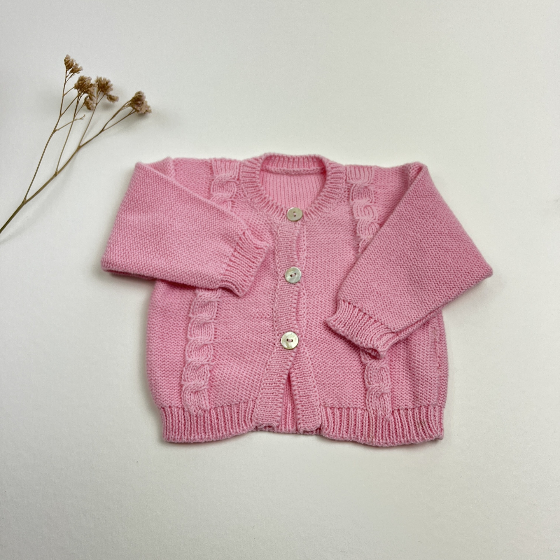 Casaco de malha rosa para criança com botões brancos e detalhe trançado