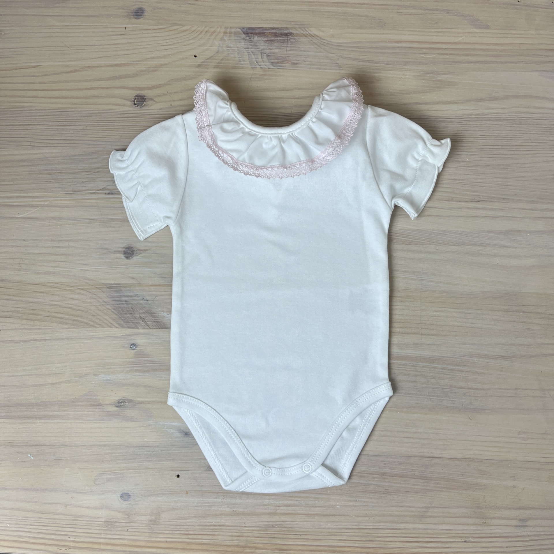 Body de bebé branco com gola de renda cor-de-rosa